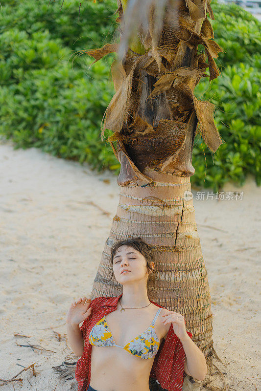 在Isla Mujeres海滩上，坐在棕榈树下的女人